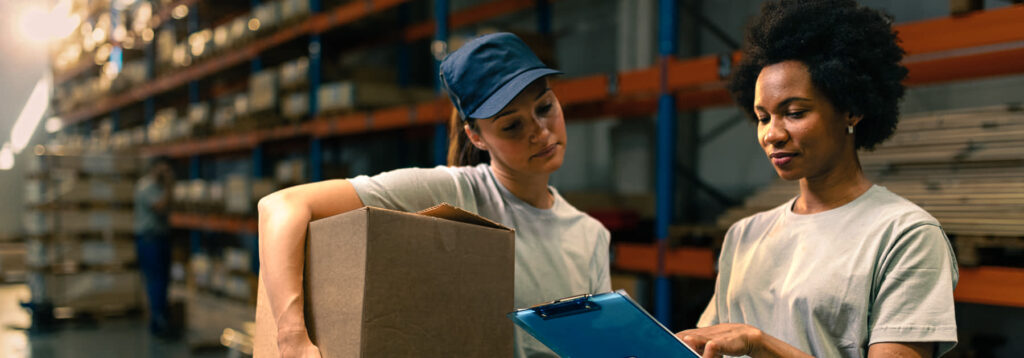 Female warehouse workers going through shipment list.