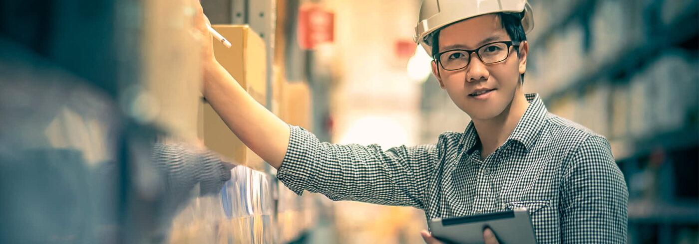 man in warehouse with hard hat holding an iPad